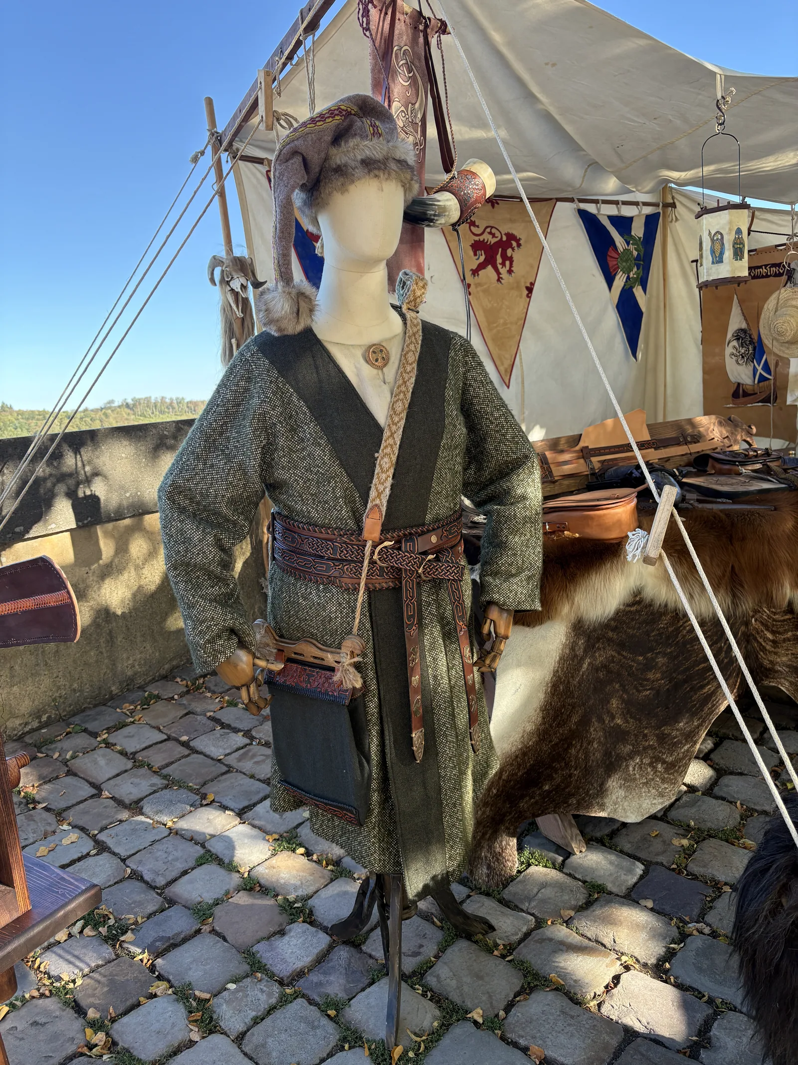 Figurine in grüner Wollgewandung mit geflochtenem Ledergürtel, Gürteltasche und Fellmütze